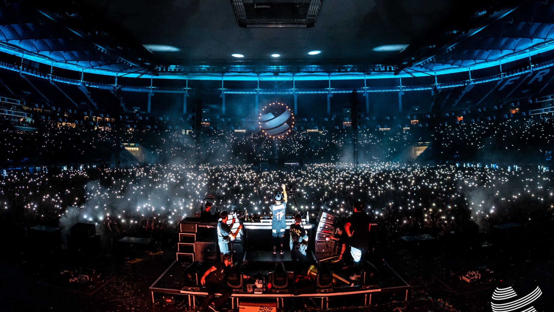 DJ performt auf der Bühne vor einer riesigen Menschenmenge im Stadion beim World Club Dome in Frankfurt, umgeben von leuchtenden Handys.