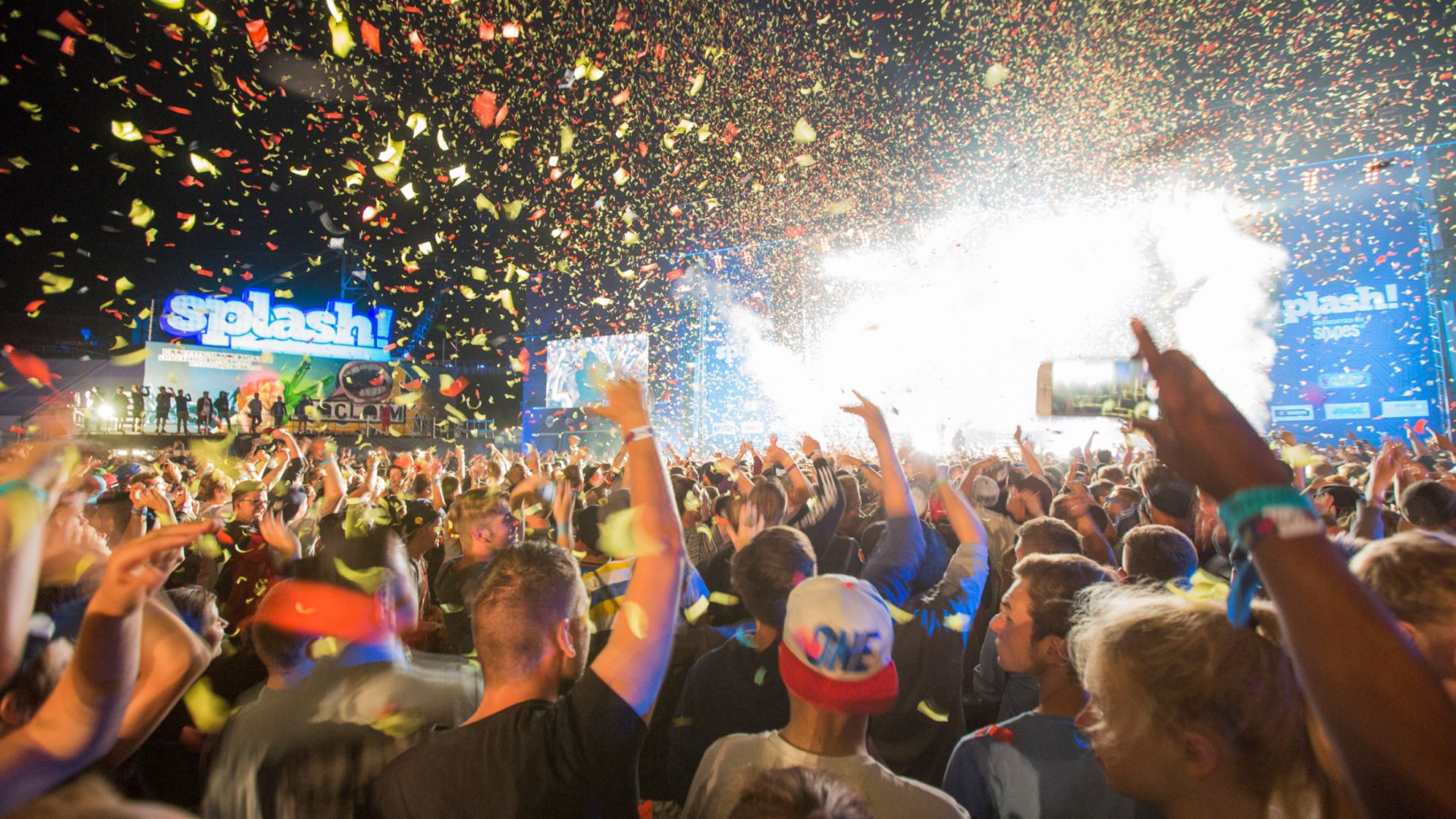 Jubelnde Menschenmenge beim Splash! Festival, umgeben von Konfetti und leuchtenden Bühnenlichtern.