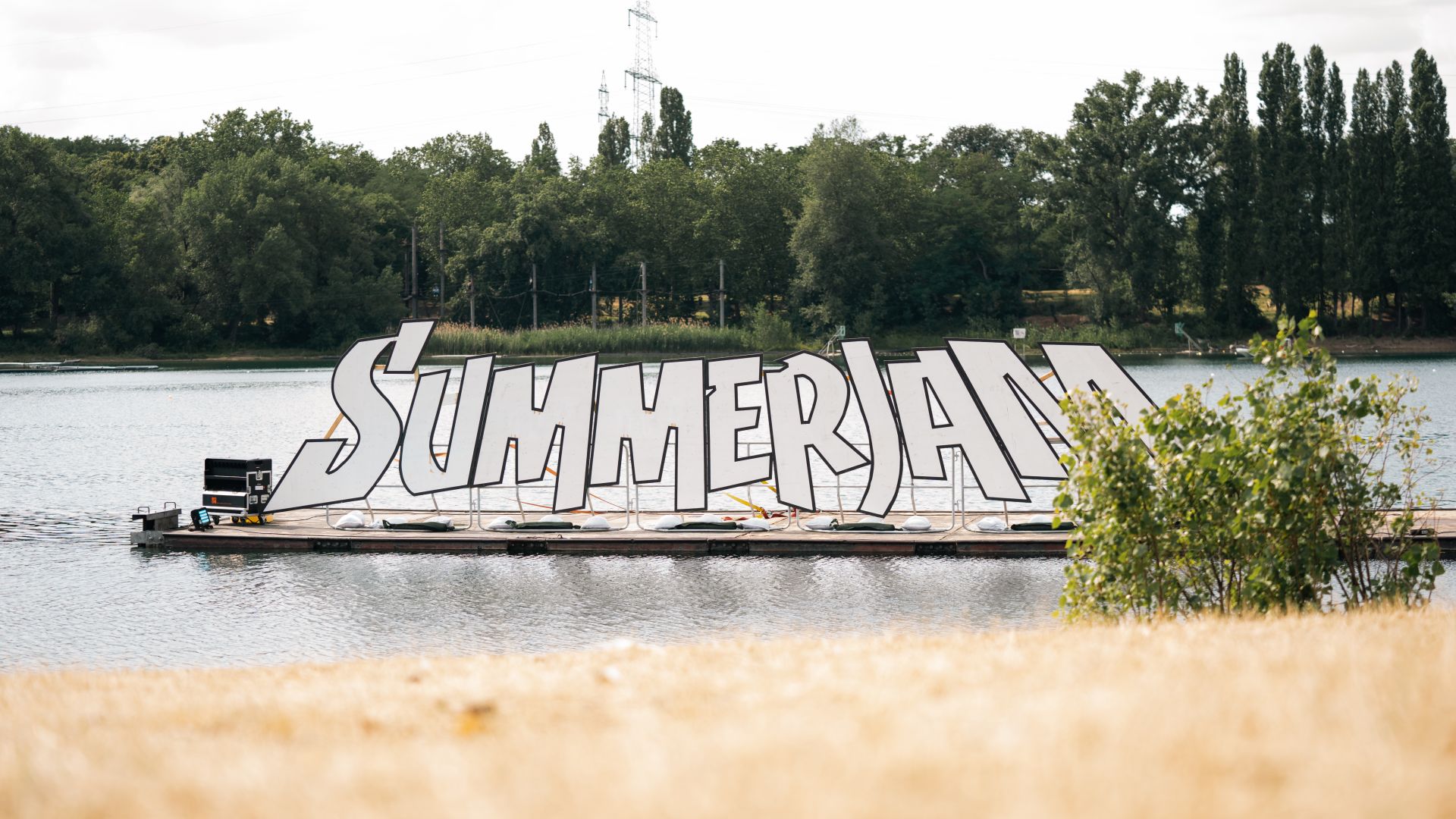 Großer 'Summerjam'-Schriftzug auf einer schwimmenden Plattform im See beim Summerjam Festival.