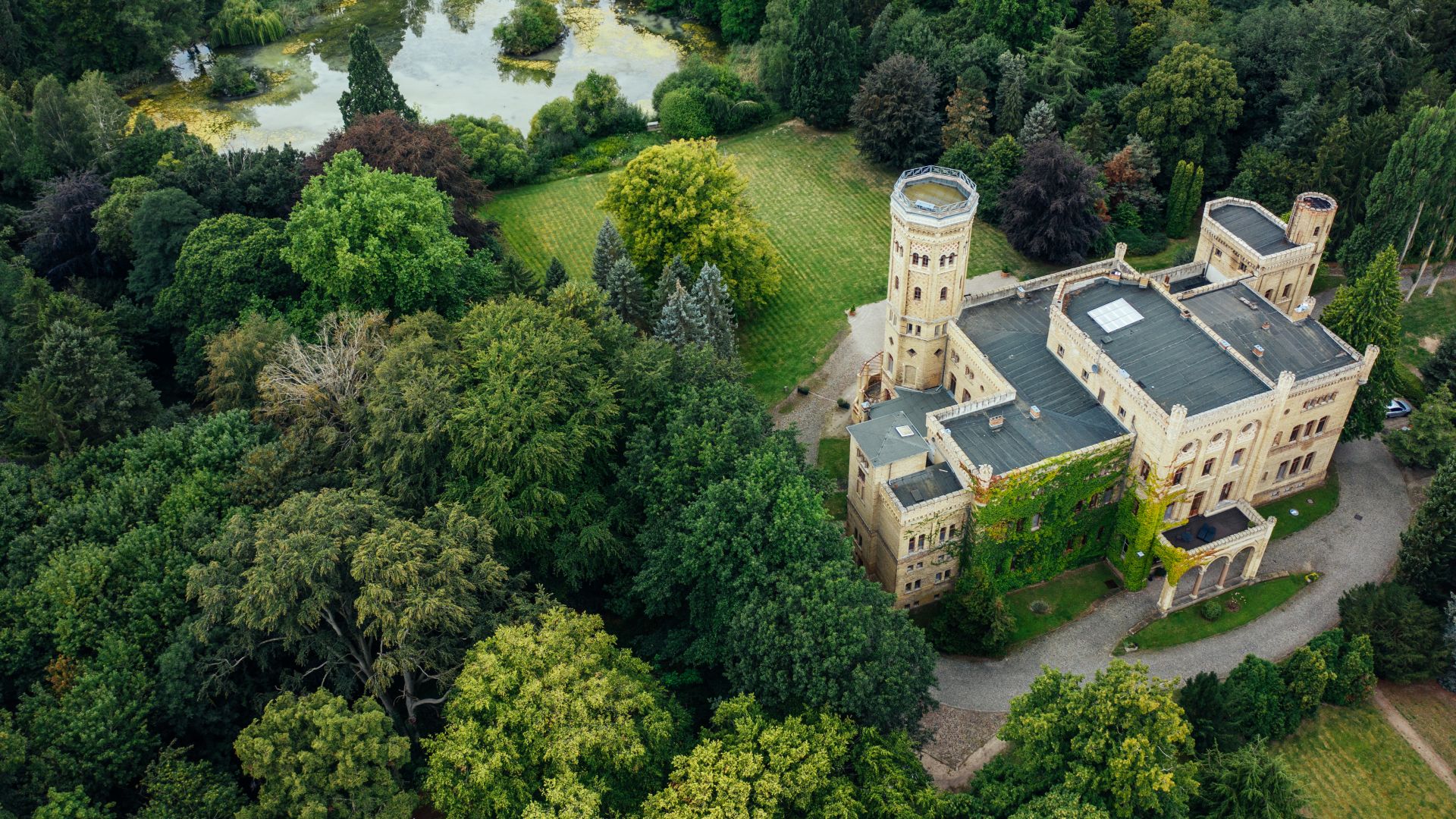 Luftaufnahme von Schloss Neetzow, umgeben von dichtem Wald und einem kleinen See.