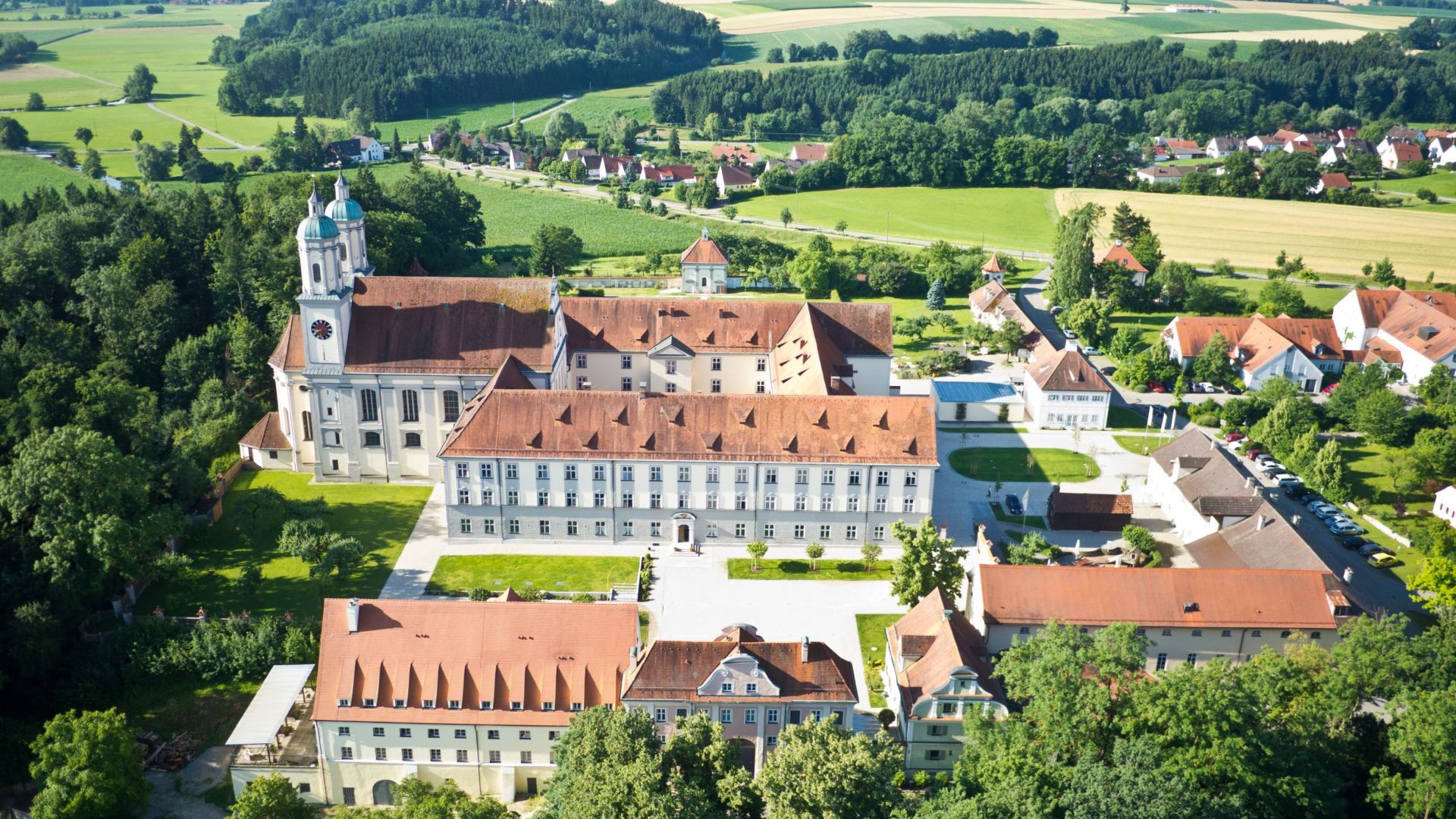 Kloster Holzen, eine historische Klosterunterkunft in Bayern, umgeben von grünen Landschaften und Feldern.