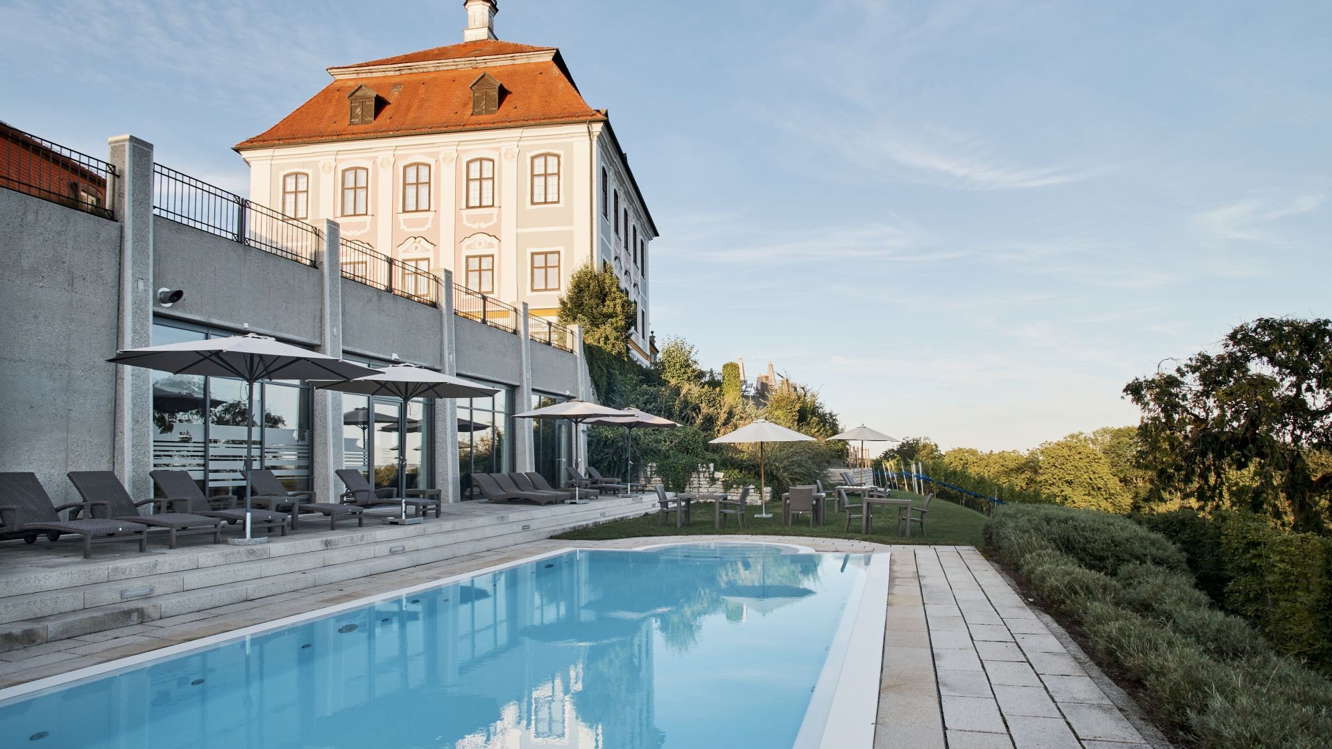 Schloss Leitheim, eine exklusive Unterkunft in Bayern, mit Pool und Terrasse, umgeben von malerischer Landschaft.