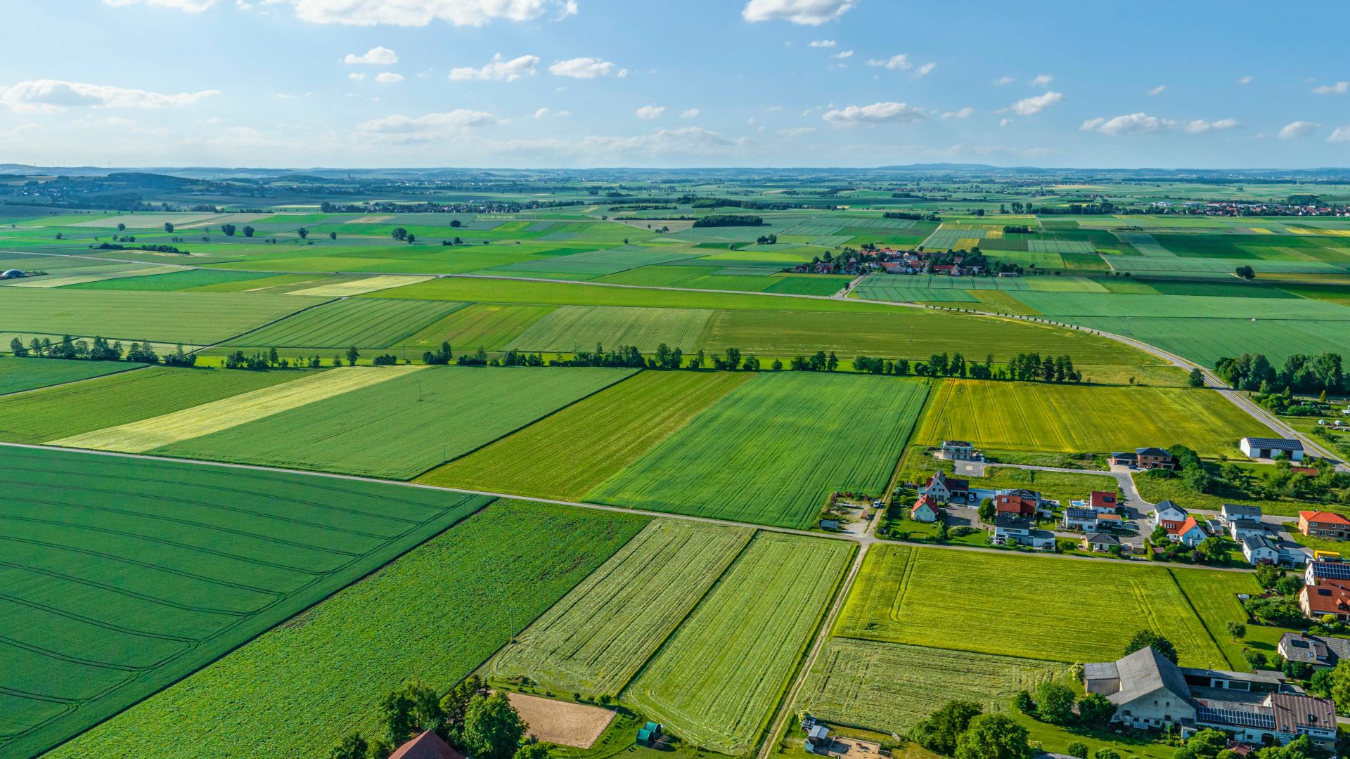 Aerial view of the Geopark Ries with green fields and small villages under a blue sky.